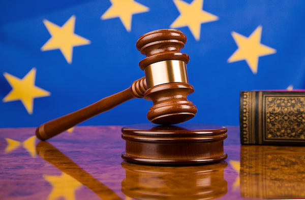 En lagbok och en domarklubba ligger på ett bord framför en EU-flagga