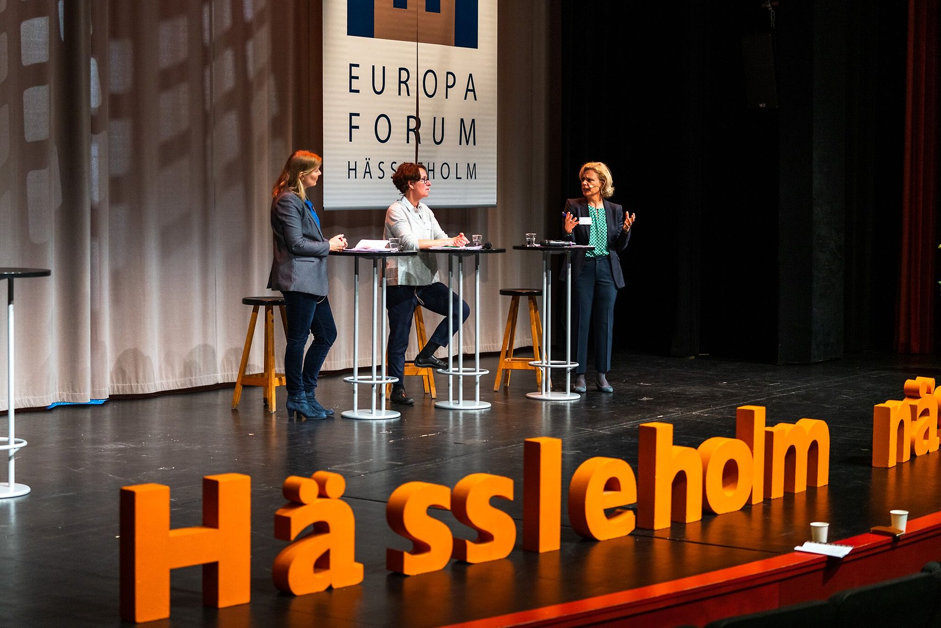 Tre talare på scenen framför en skylt med texten Europaforum Hässleholm